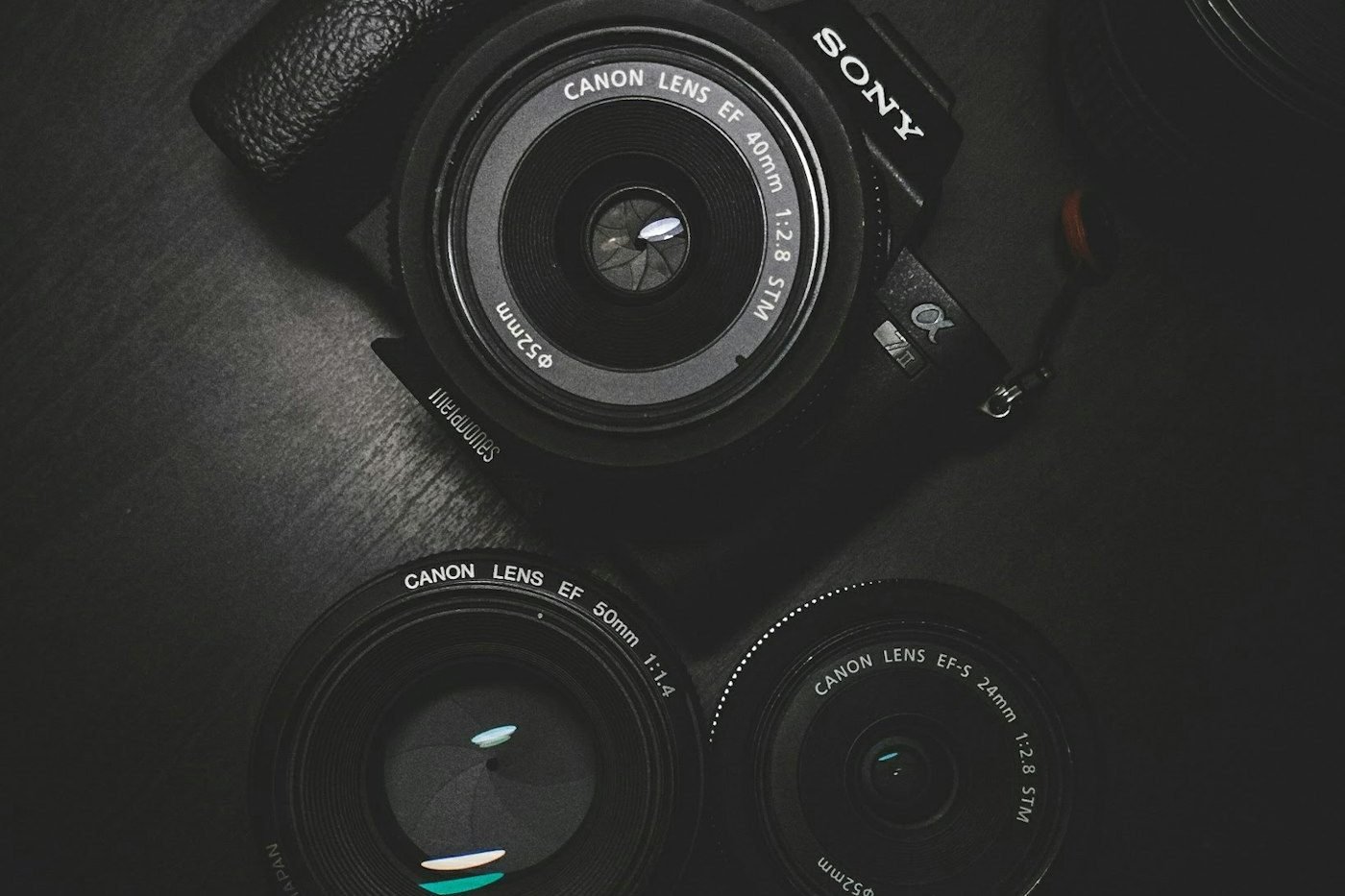 Koyu zeminde profesyonel fotoğraf makinesi gövdesi ve objektifler
